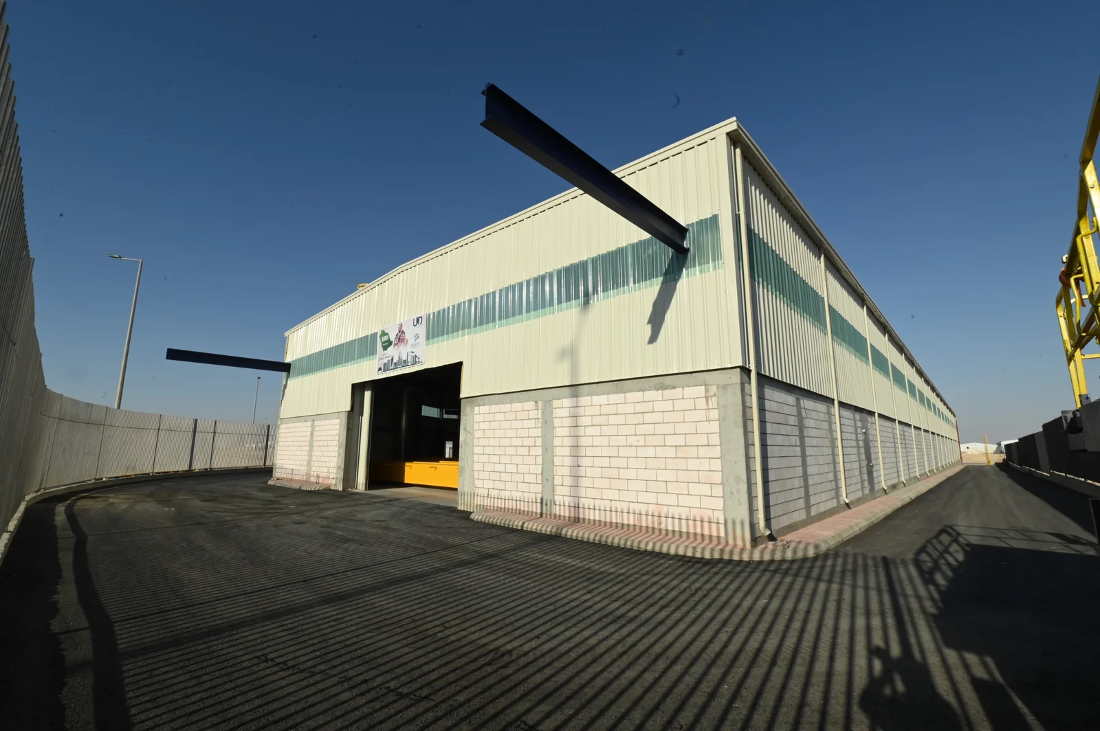 Completed steel-framed industrial hall with a beam being lifted